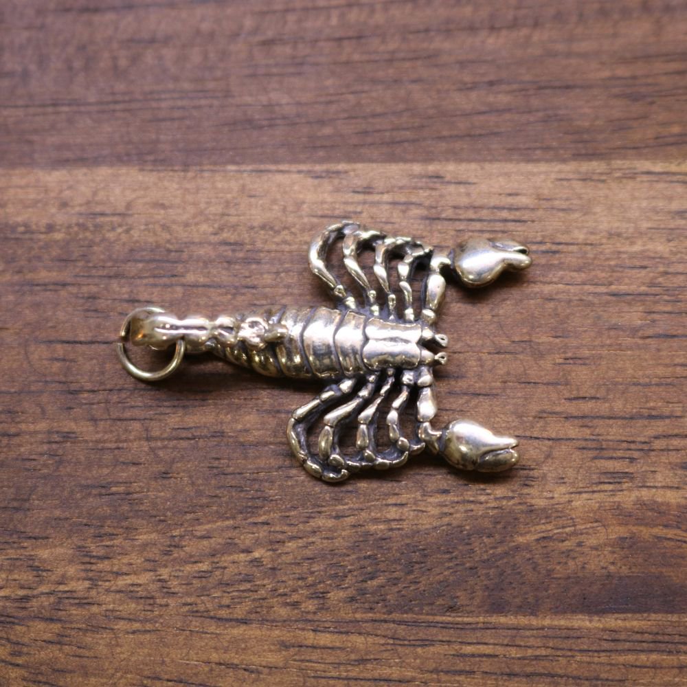 a metal scorpion on a wood surface