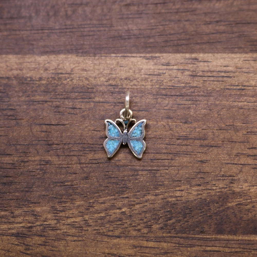 a butterfly pendant on a wood surface
