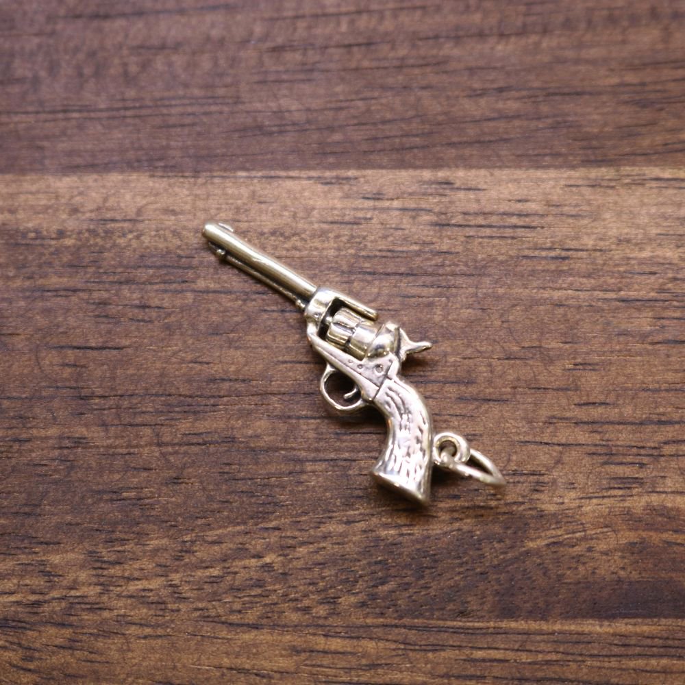 a small gun shaped keychain on a wood surface