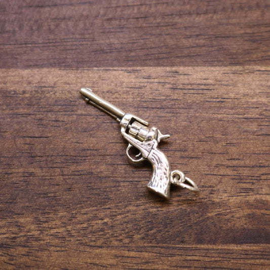 a small gun shaped keychain on a wood surface
