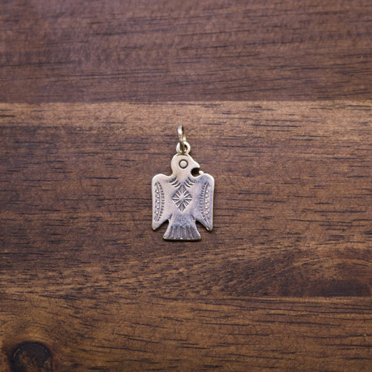 a metal bird pendant on a wood surface