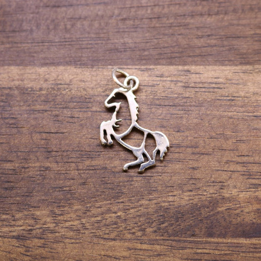 a metal horse pendant on a wood surface