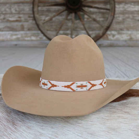 a brown hat with a beaded band on a white fur rug
