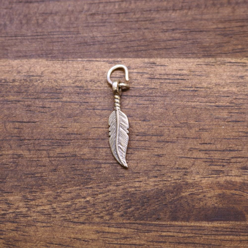 a feather shaped pendant on a wood surface