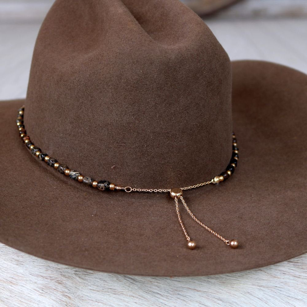 a brown hat with a beaded necklace