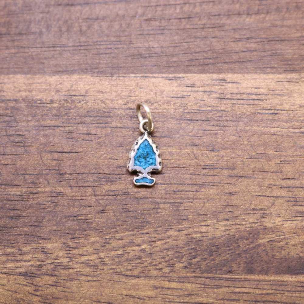 a blue and gold pendant on a wood surface