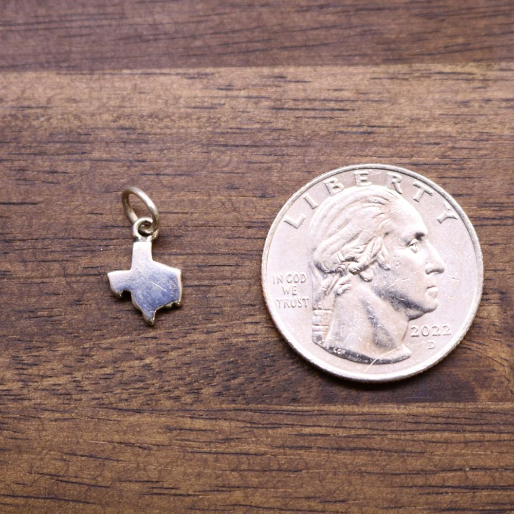 a coin and a pendant on a wood surface