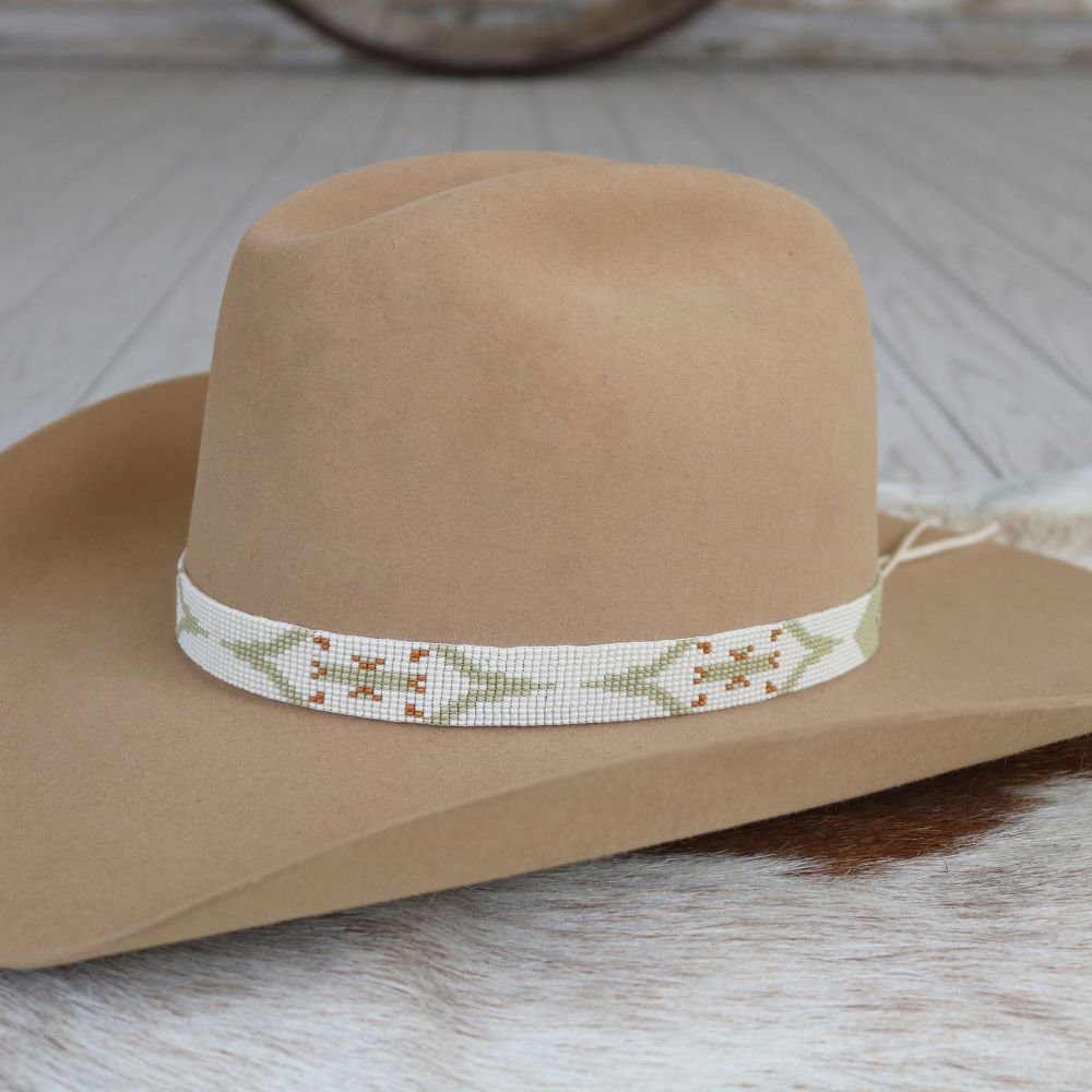 a brown hat with a beaded band on a white fur surface