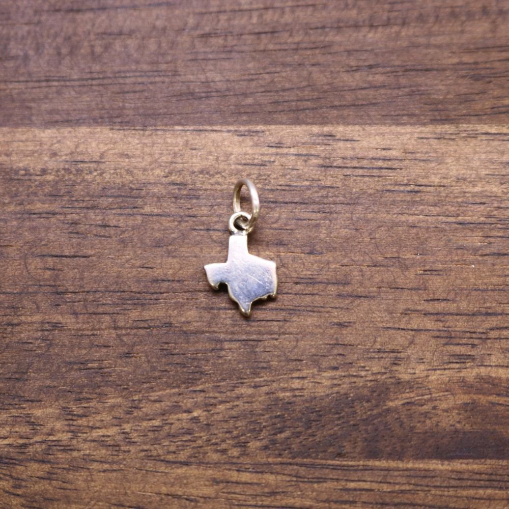 a gold texas state pendant on a wood surface