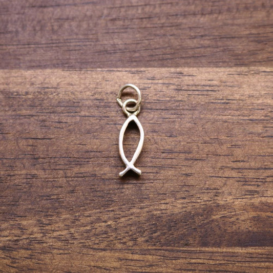 a small gold fish pendant on a wood surface