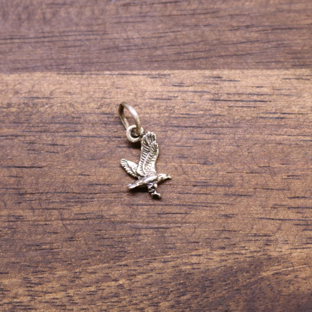 a gold eagle charm on a wood surface
